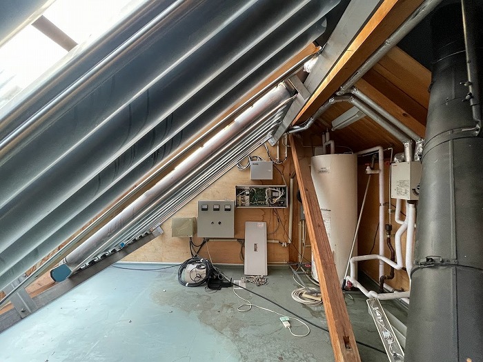 　太陽熱給湯パネルと給湯器が置かれた屋根裏の物干しスペース（筆者撮影，2022年10月）